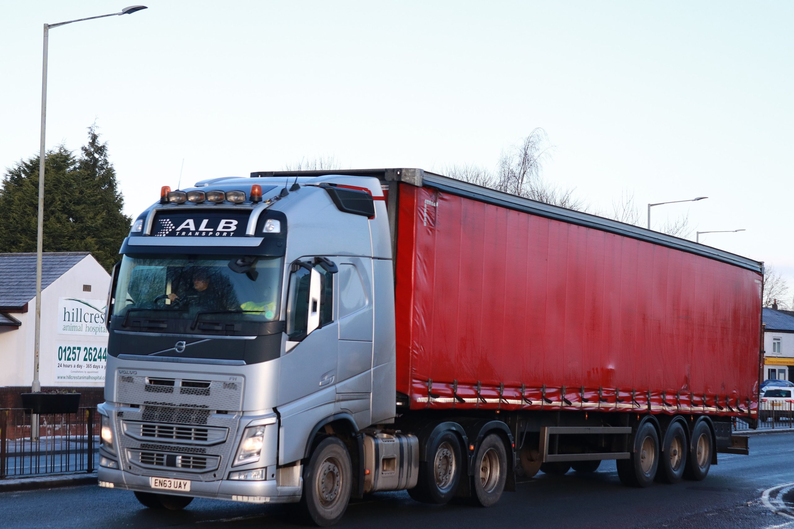 Red curtain-sided semi-trailer behind a Volvo FH tractor unit